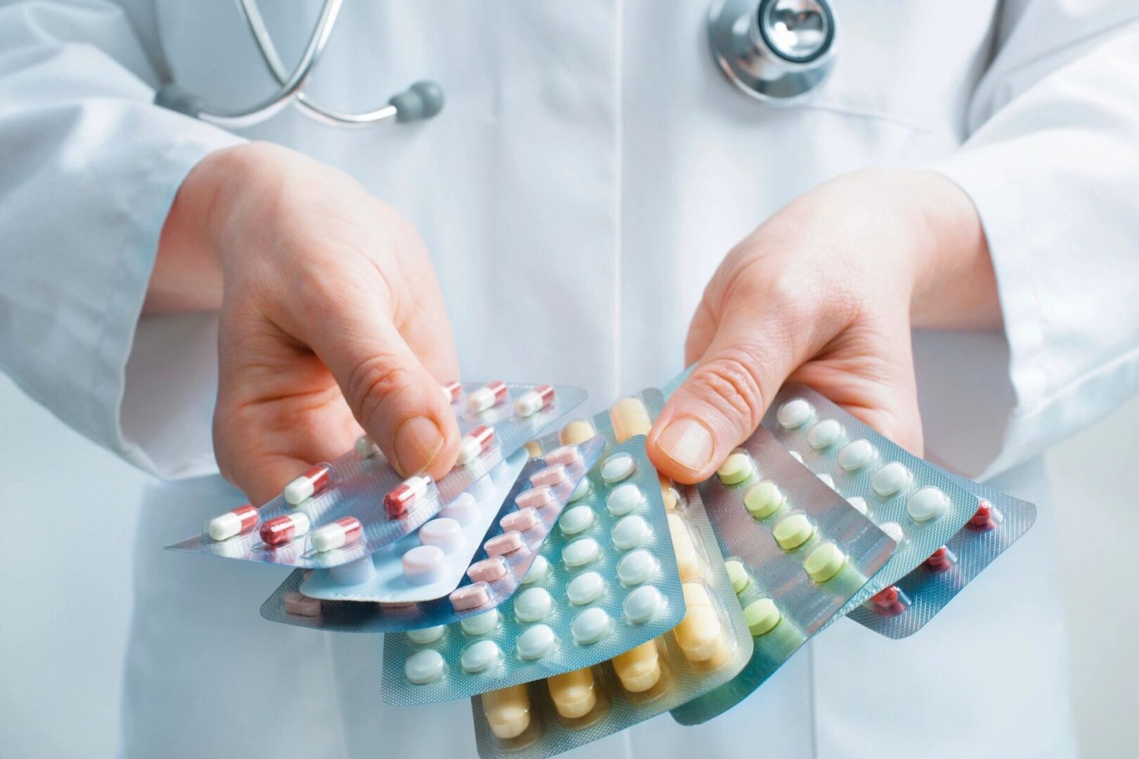 A doctor holding several different types of pills.